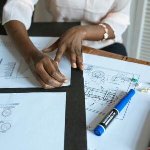 An adult working on business charts and design blueprints in an office setting.