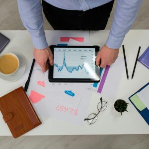 Overhead view of businessman using tablet to review data charts at a modern office desk.